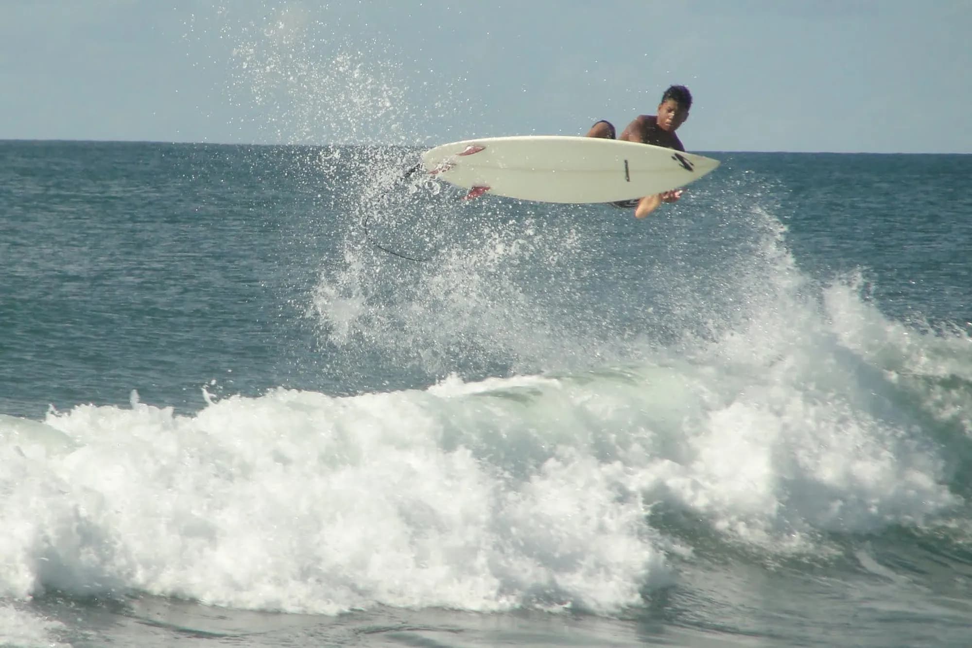 Surfer catches air above breaking wave