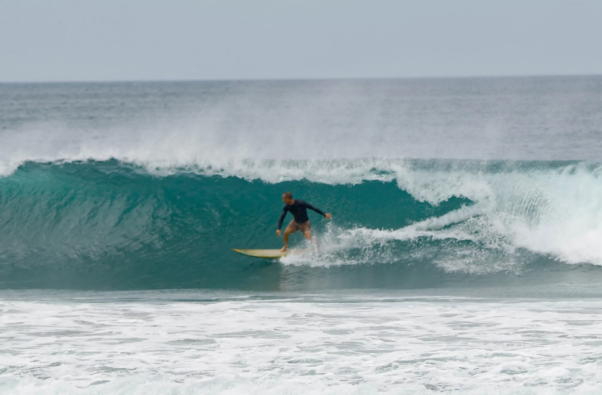 Surfer @r-b gracefully riding a clean right barrel wave.